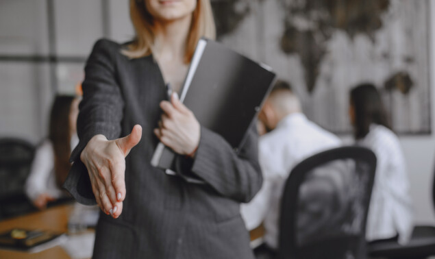 Woman in a suit holds a folder.