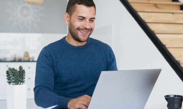 homme-souriant-travaillant-sur-un-ordinateur-portable-a-la-maison